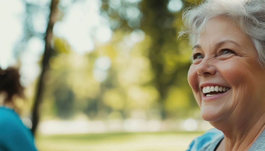 Eine lächelnde ältere Frau genießt eine Outdoor-Aktivität an einem sonnigen Tag in einem Park.